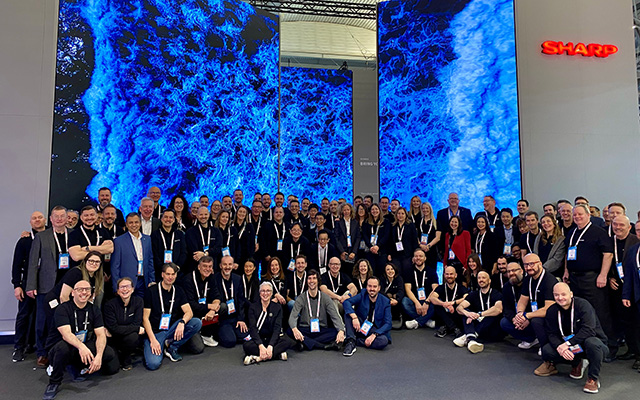 A crowd of people sit in front of a LED video wall